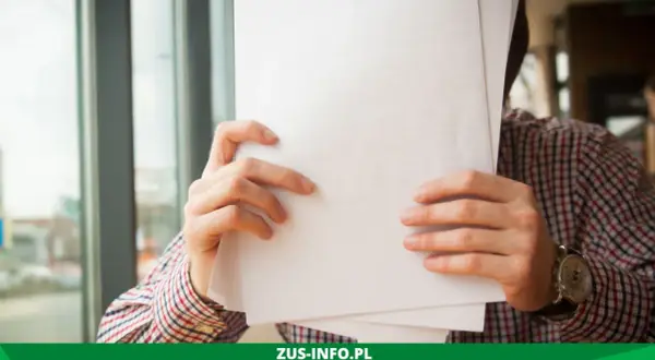 Mężczyzna w kratę trzyma dokumenty, być może wniosek o niezaleganie ZUS.