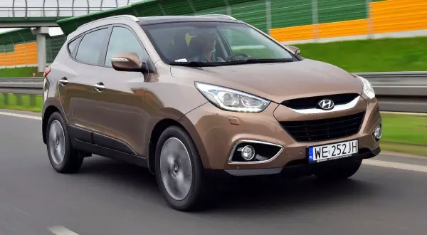 Brązowy Hyundai ix35 w ruchu drogowym, z widocznym kierowcą.