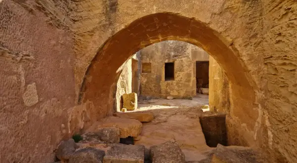 Kamienne łuki i korytarze w grobowcach królewskich Pafos, gdzie słońce rzuca długie cienie na starożytne mury.