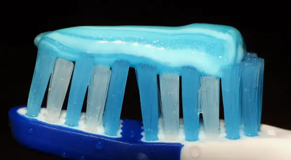 Pasta de dientes azul y blanca sobre cerdas de cepillo, lista para una limpieza. ¿Cómo lavarse los dientes sin cepillo? ¡Imposible!
