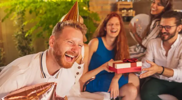 Impreza urodzinowa w pełni! Wesołe twarze, prezent i balony. Idealne krótkie życzenia urodzinowe - śmieszne, bo radość jest najważniejsza!