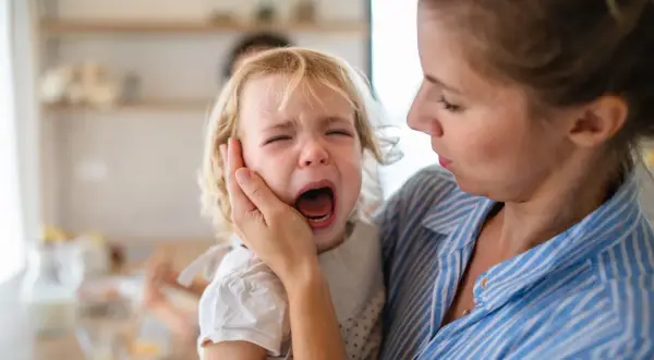 Niña rubia llorando desconsoladamente mientras una mujer la consuela.
