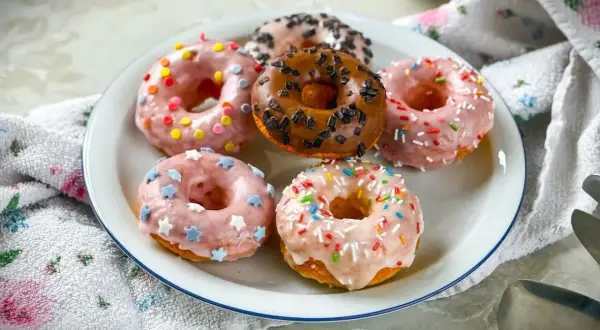 Sechs bunte Donuts, die Lust aufs **Donuts selber machen** machen: Rosa mit Sternen, pink mit bunten Streuseln, braun mit Schokostreuseln und weitere.