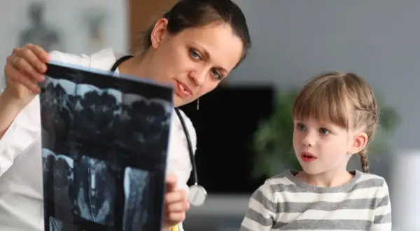 Lekarka, być może neuropsycholog, pokazuje dziecku wyniki rezonansu.