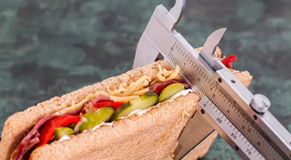 Messung eines Sandwiches mit einem Messschieber, um die Kalorienaufnahme zu kontrollieren. Vielleicht 1500 Kalorien am Tag?