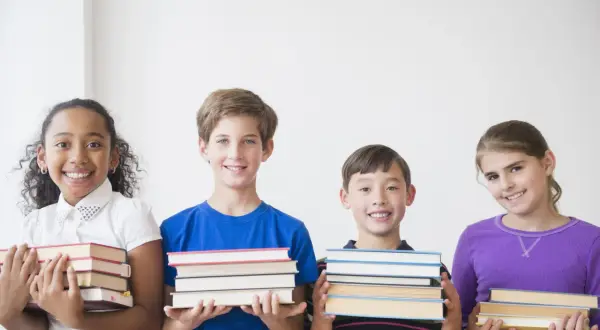 Vier lächelnde Kinder der 3. Klasse präsentieren stolz ihre Bücher für die buchvorstellung klasse 3.