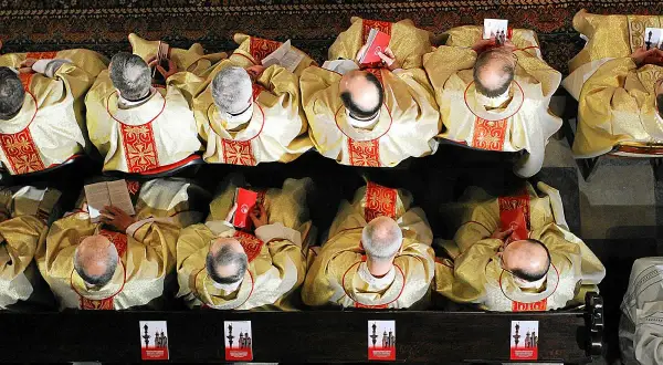 Księża w złotych szatach, z czerwonymi zdobieniami, siedzą w ławkach, czytając księgi. Ich skupienie przypominało dawnych pogan podczas rytuałów.