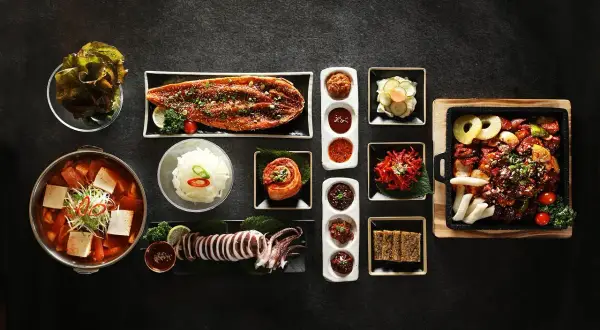 Zestaw koreańskich potraw: zupa, ryba, kalmar, kimchi, ryż i dodatki.