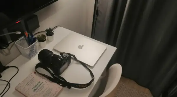 Na biurku leży aparat Nikon 3100, obok książka "Classical Mechanics" i laptop.
