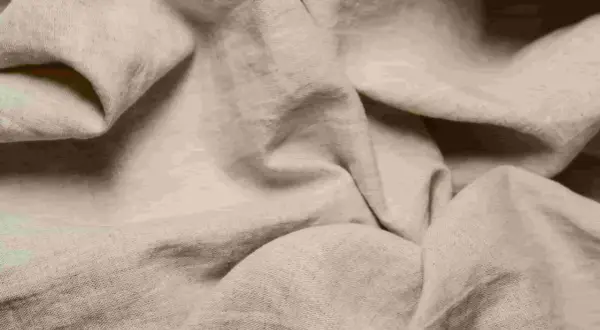 Miękki, beżowy len układa się w faliste fałdy, idealny na letnie upały.