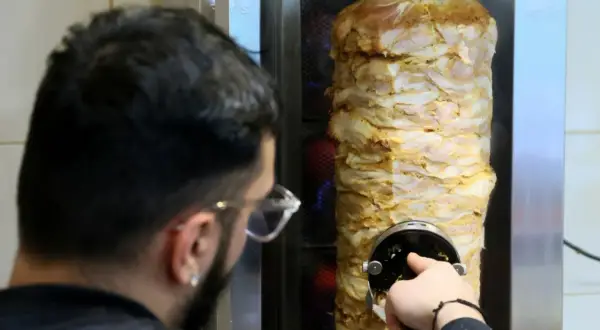 Kebab jakie mięso? Obracający się pionowo rożen z soczystym, przyprawionym mięsem drobiowym, gotowym do krojenia.