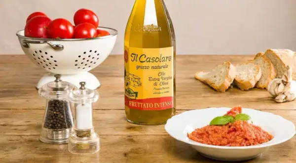 Un plat de pappa al pomodoro, garni de basilic, avec des tomates fraîches, du pain, de l'huile d'olive et des moulins à poivre et sel.