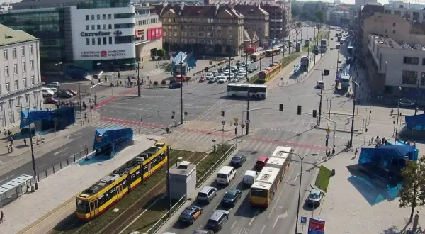 Żółty tramwaj na skrzyżowaniu z samochodami i autobusem.