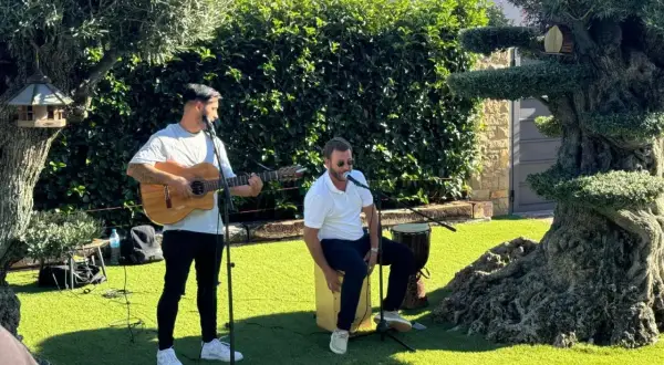 Dos músicos animan el jardín con rumbas para bailar. Uno toca la guitarra y canta, el otro canta y percute un cajón.