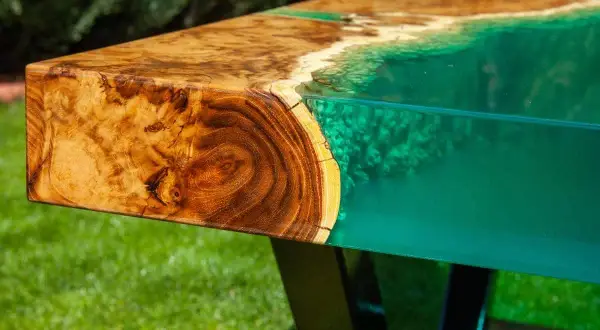 Tavolo con venature di legno e resina epossidica verde brillante, che ricorda un paesaggio marino. Attenzione: la resina epossidica è tossica.