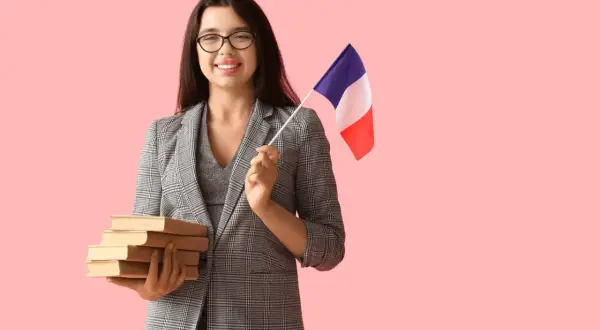 Uśmiechnięta kobieta w okularach trzyma stos książek i flagę Francji, gotowa by zostać francuskim pisarzem.