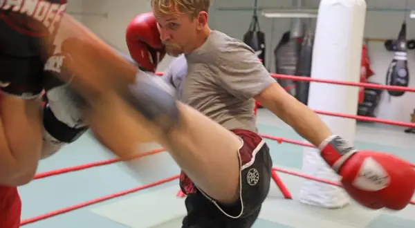 Man i thai-boxningsring i Sverige utför en spark. Träningspass med thai mora.