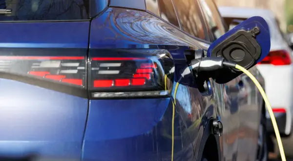 Niebieski samochód hybrydowy jest ładowany. To przyszłość motoryzacji, która łączy silnik spalinowy z elektrycznym.