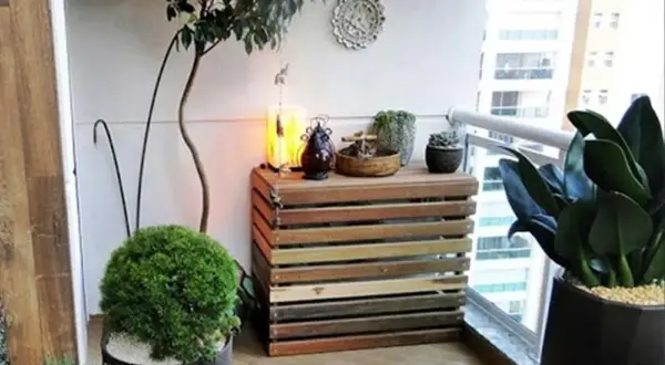 Mueble de madera para tapar unidad exterior aerotermia, decorado con plantas y objetos.