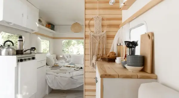 L'habitacle du camion aménagé offre une cuisine fonctionnelle et un coin couchage douillet, décoré d'une macramé murale.