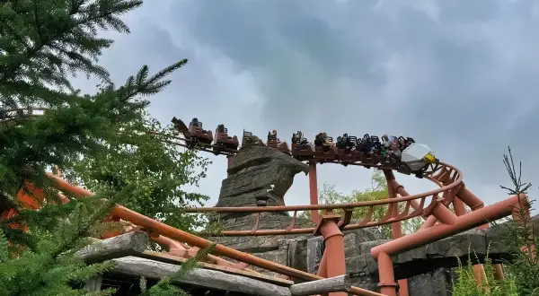 Kolejka górska w Legolandzie Niemcy z pasażerami pędzi po torach wśród skał i zieleni.