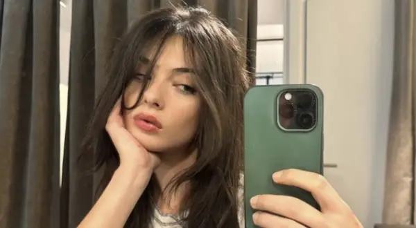 Deva Cassel se toma un selfie con su teléfono, apoyando la barbilla en la mano.
