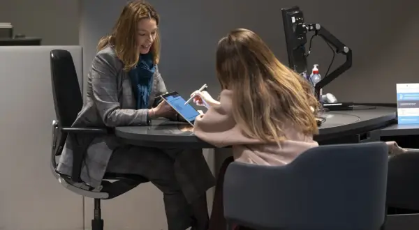 Dos mujeres revisan una tablet, discutiendo una posible hipoteca de 100.000 euros a 15 años.