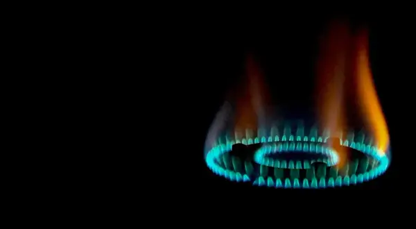 Fiamma gialla e blu di un bruciatore a gas, parte di una caldaia, che illumina il buio.