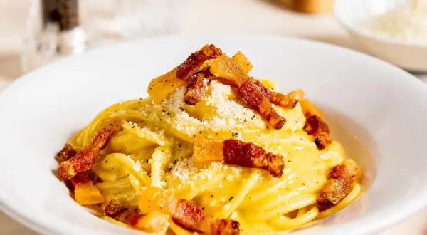 Ein Teller mit authentischer Spaghetti Carbonara, garniert mit knusprigem Guanciale und Pecorino. Ein wahrer Genuss der italienischen Küche.