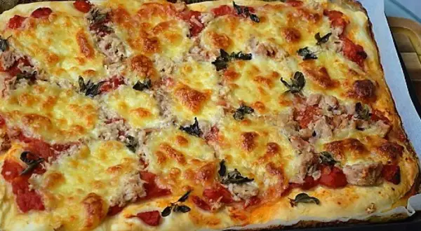 Pyszna, domowa pizza z tuńczykiem, zapieczona pod złotym serem z dodatkiem pomidorów i ziół.