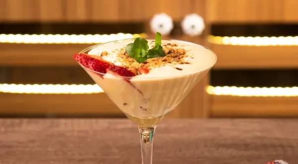 Delicioso sabayon de huevo en copa de martini, decorado con fresas y menta.