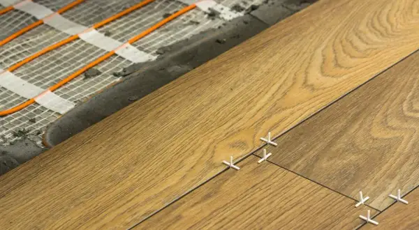 Układanie podłogi z ogrzewaniem podłogowym w salonie 30 m2. Widoczne pętle grzewcze i nowe płytki.