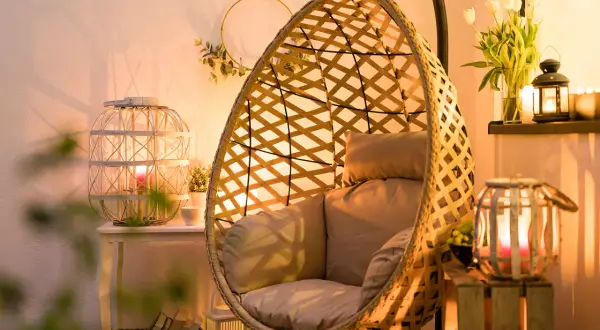 Przytulny salon z fotelem wiszącym i lampionami w aranżacjach tworzącymi ciepłą atmosferę.