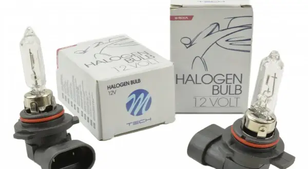 Dwie żarówki halogenowe M-Tech 12V obok pudełek. Idealne do Twojego samochodu, zapewniające jasne światło.