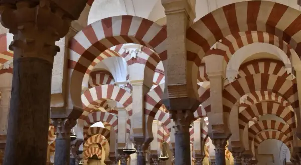 Columnas y arcos de herradura bicolores en la Mezquita de Córdoba, un ejemplo de sus diversos estilos arquitectónicos.