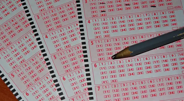 Kupony lotto z zaznaczonymi liczbami i ołówkiem. Zastanawiasz się, dlaczego niektórzy gracze zostawiają w kolekturach tylko niedrapane kody?