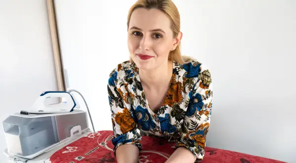 Kobieta z uśmiechem na twarzy, obok stacji parowej. Dowiedz się, co zrobić, żeby materiał się nie gniótł i wyglądał perfekcyjnie.