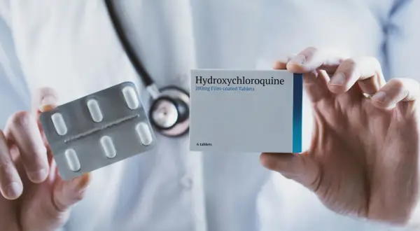 Lekarz prezentuje opakowanie Hydroxychloroquine Adamed i blister z tabletkami.