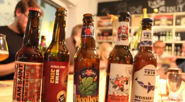 Fünf Flaschen Craft Beer stehen nebeneinander. Jede Flasche hat ein einzigartiges Etikett, das die Vielfalt von Craft Beer zeigt.