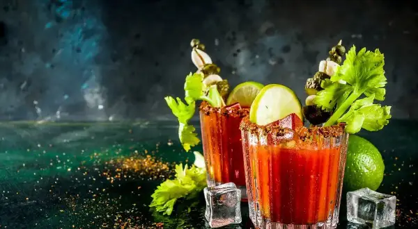 Dwa drinki Krwawa Mary z łodygami selera, limonką i piklami. Idealny przepis na brunch.