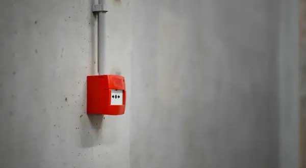 Découvrez comment fonctionne une alarme incendie : un boîtier rouge sur un mur en béton, prêt à alerter en cas de danger.