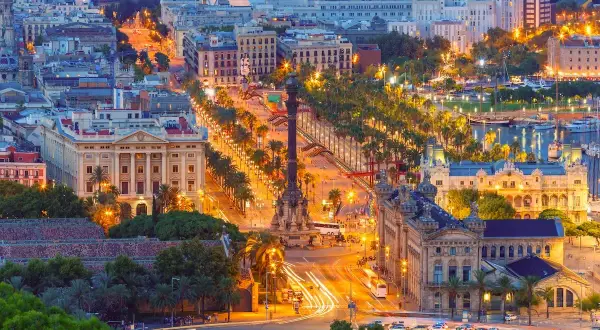 Vista aerea di Barcellona di notte, con la Rambla illuminata, palme e locali notturni che brillano.