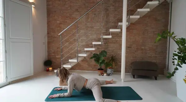 Donna in posizione rana yoga, con le ginocchia divaricate e il busto appoggiato sugli avambracci.