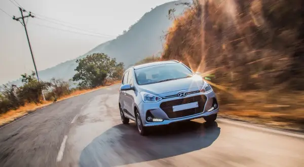 Srebrny Hyundai pędzi po krętej drodze wśród wzgórz. Czy hyundai ma ocynkowane blachy? To pytanie o jego trwałość.
