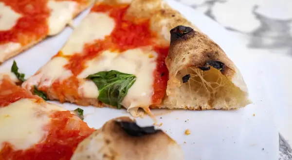 Pyszna pizza neapolitańska przepis na klasyk z pomidorami, mozzarellą i bazylią. Idealnie wypieczone ciasto z pęcherzykami powietrza.