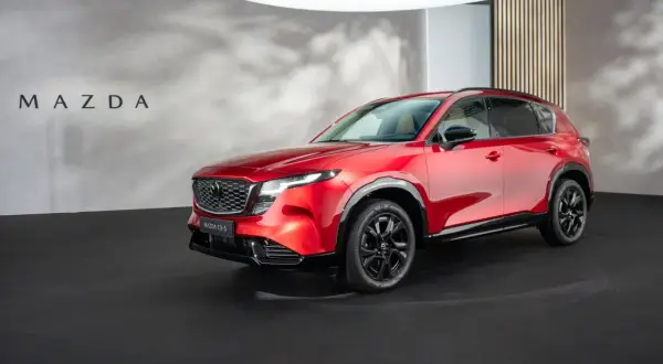 Lśniąca, czerwona Mazda CX-5 2026 prezentuje się na czarnej scenie.