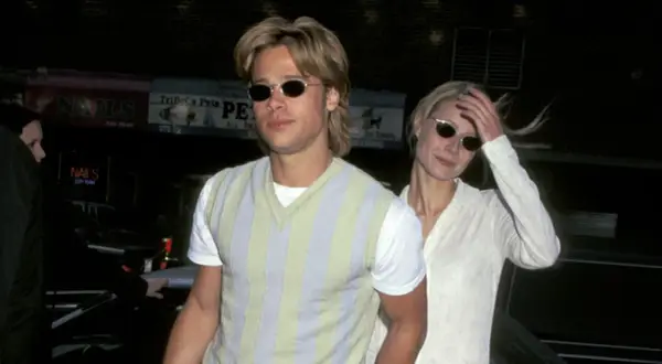 Brad Pitt joven con gafas de sol y un suéter a rayas, junto a una mujer rubia.