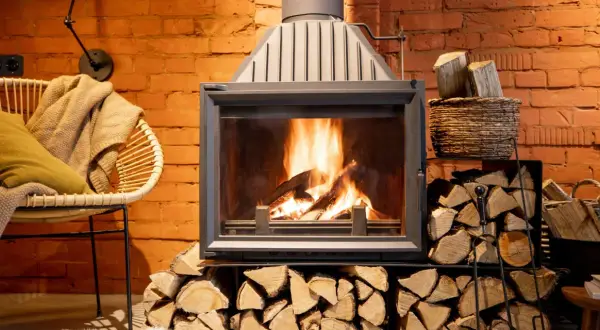 Le feu crépite dans la cheminée, mais la fumée refoule. Un fauteuil confortable et des bûches attendent.