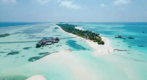 Rajska **Malediwy plaża** z turkusową wodą, białym piaskiem, palmami i luksusowymi domkami na wodzie.