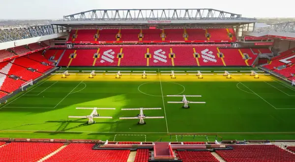 Piękny stadion w Anglii, Anfield, z czerwonymi trybunami i zieloną murawą, gotowy na kolejne emocjonujące mecze.